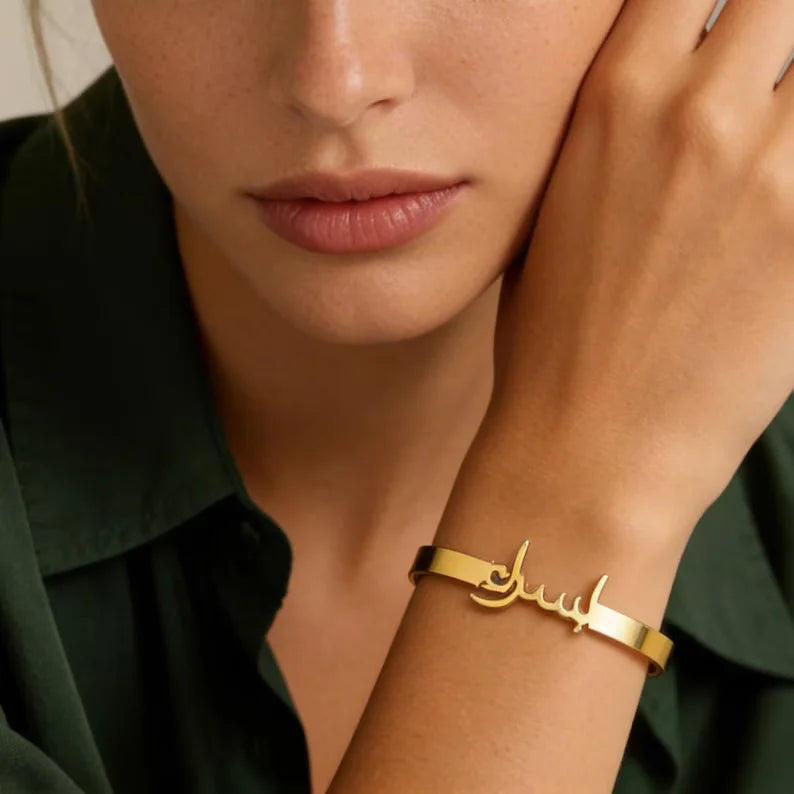 Arabic name bracelet with custom calligraphy lettering integrated into a polished golden band, styled as a personalised jewellery piece.