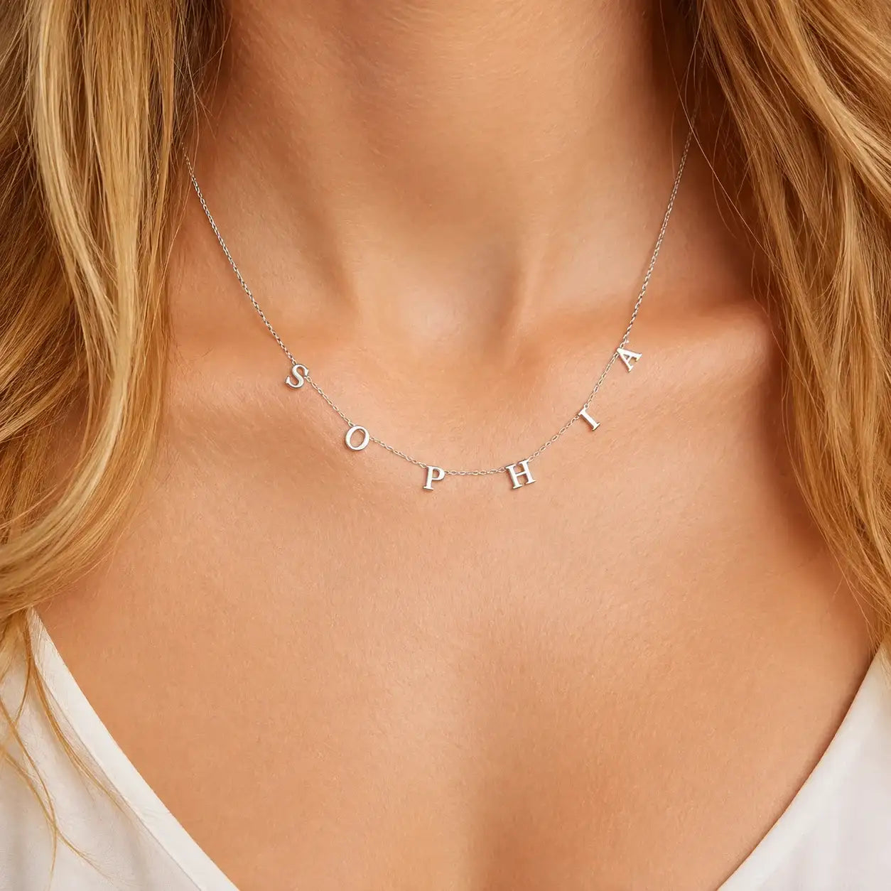 Woman wearing silver chain necklace with individually spaced block letters spelling Sophia