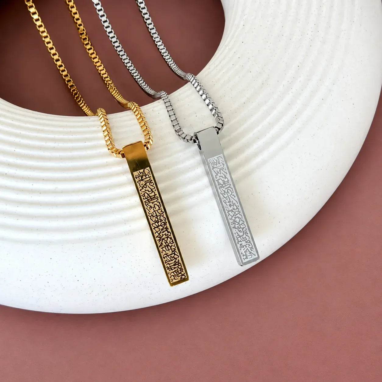 Gold and silver colored Ayat Ul Kursi bar necklaces with engraved Arabic calligraphy.