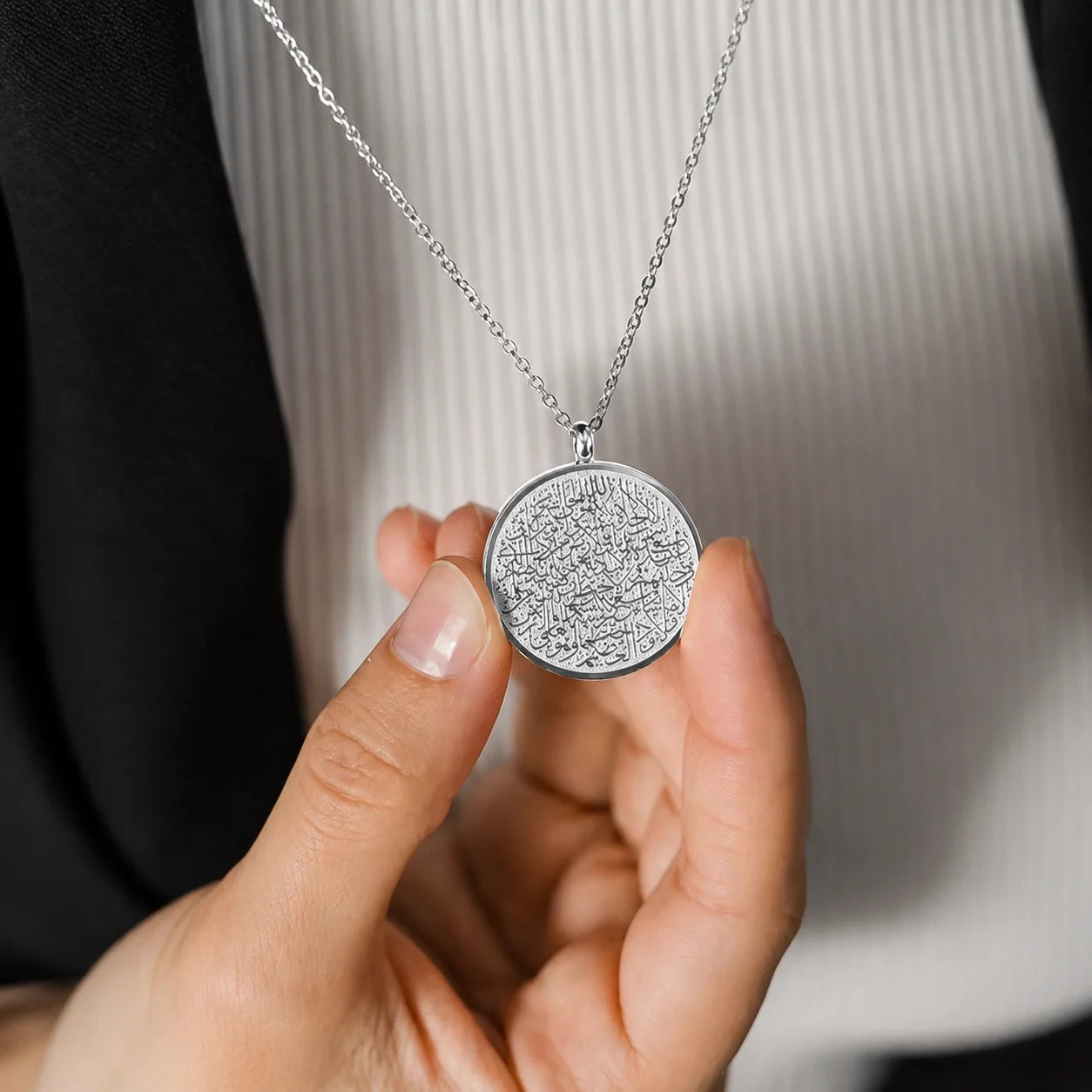 Silver Ayat ul Kursi pendant necklace with intricate Arabic calligraphy held by hand, ideal for everyday Islamic jewelry.