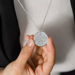 Silver Ayat ul Kursi pendant necklace with intricate Arabic calligraphy held by hand, ideal for everyday Islamic jewelry.