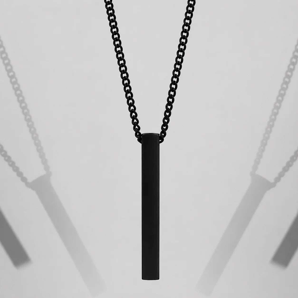 Matte black curb chain necklace with vertical 3D bar pendant centered on light grey background