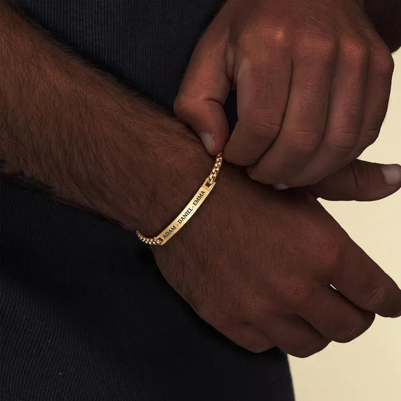 Personalized golden  bracelet with custom engraved names on a curb chain.