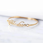 Custom name bangle featuring a script-style personalised name across a sleek open cuff bracelet design.
