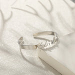 A polished silver open cuff bracelet engraved with the name natasha.