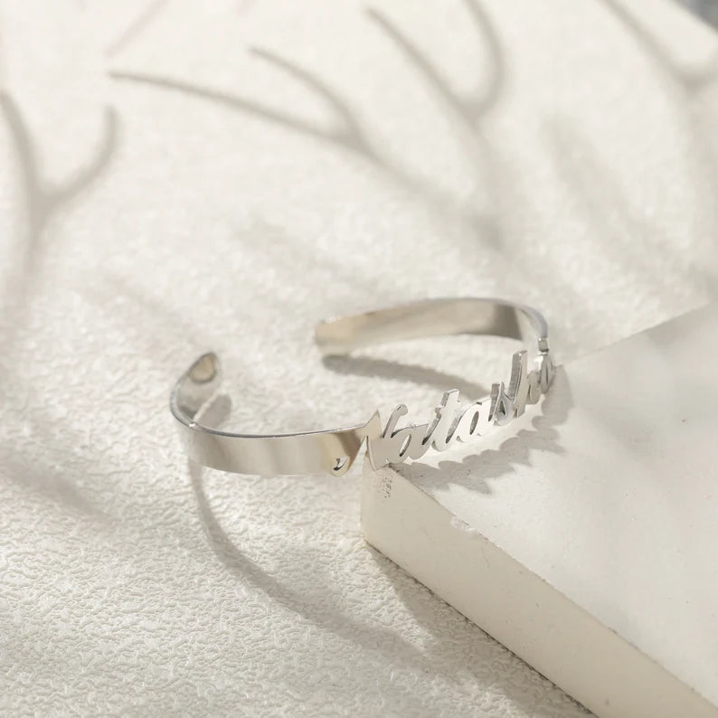 A polished silver open cuff bracelet engraved with the name natasha.