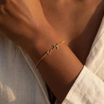 Custom name chain bracelet featuring personalised script lettering on a delicate chain, worn around the wrist in a golden finish.