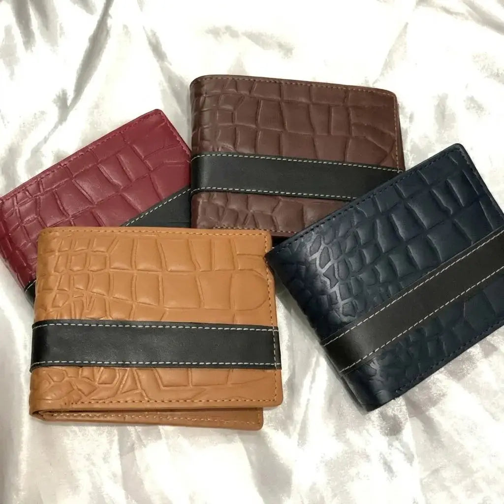 Four foldover crocodile-embossed leather wallets in tan, navy blue, brown, and red on white fabric.