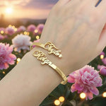 Custom two name bangle featuring two personalised script names across an open polished cuff bracelet, shown in a golden finish.