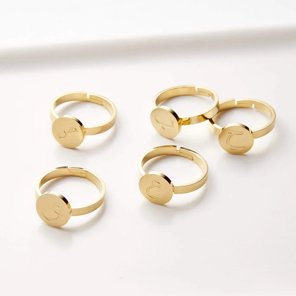 Collection of five adjustable gold disc rings featuring engraved Arabic calligraphy characters