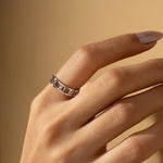 A close-up of a hand wearing a silver ring with Roman numerals, set against a warm beige background.