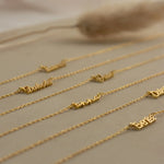 Gold name necklaces on a neutral background