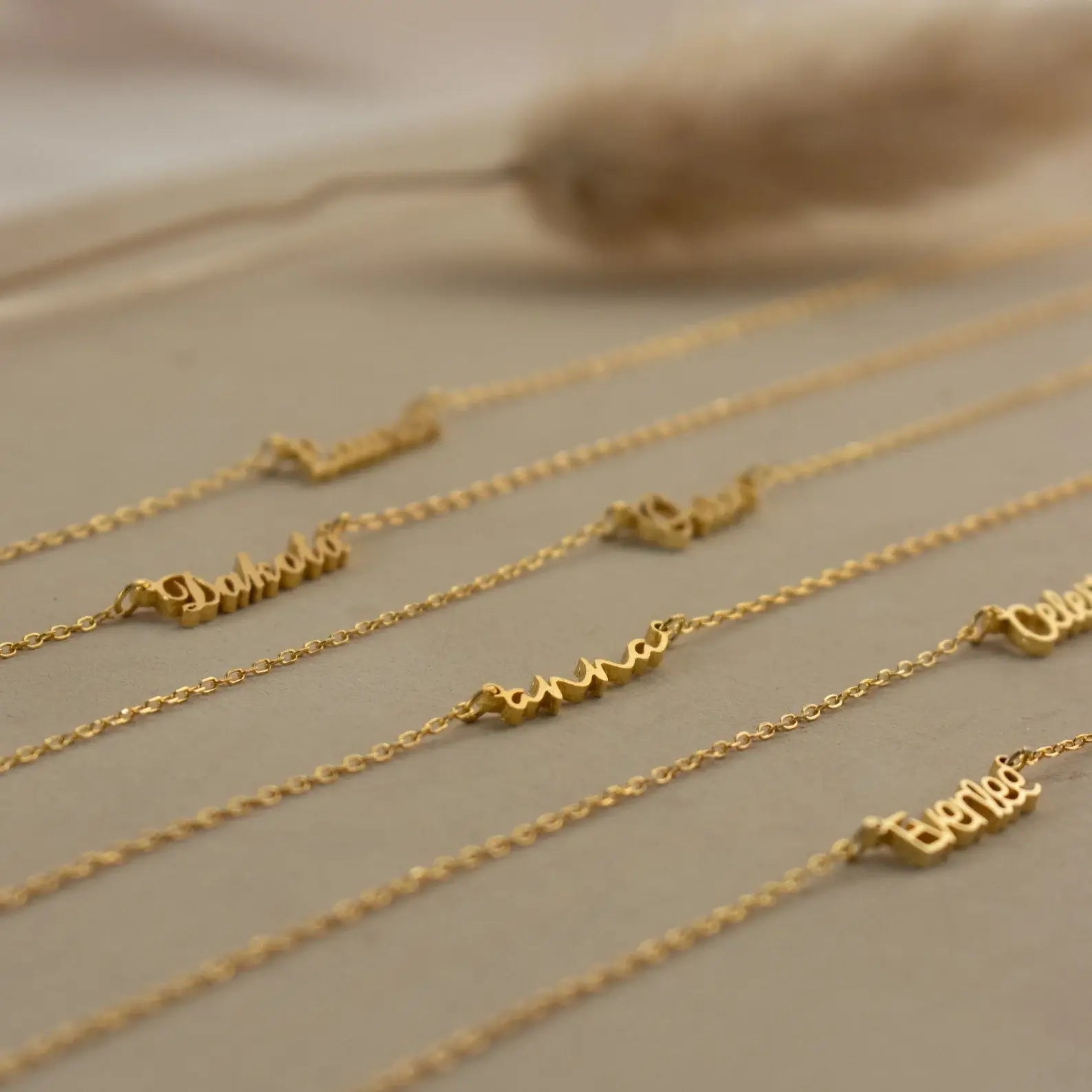 Gold name necklaces on a neutral background