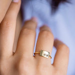 Woman wearing thin gold band ring with flat rectangular plate engraved with cursive BB initials