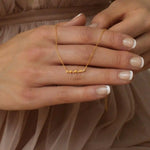 Hand holding delicate gold chain necklace with lowercase anna cursive nameplate