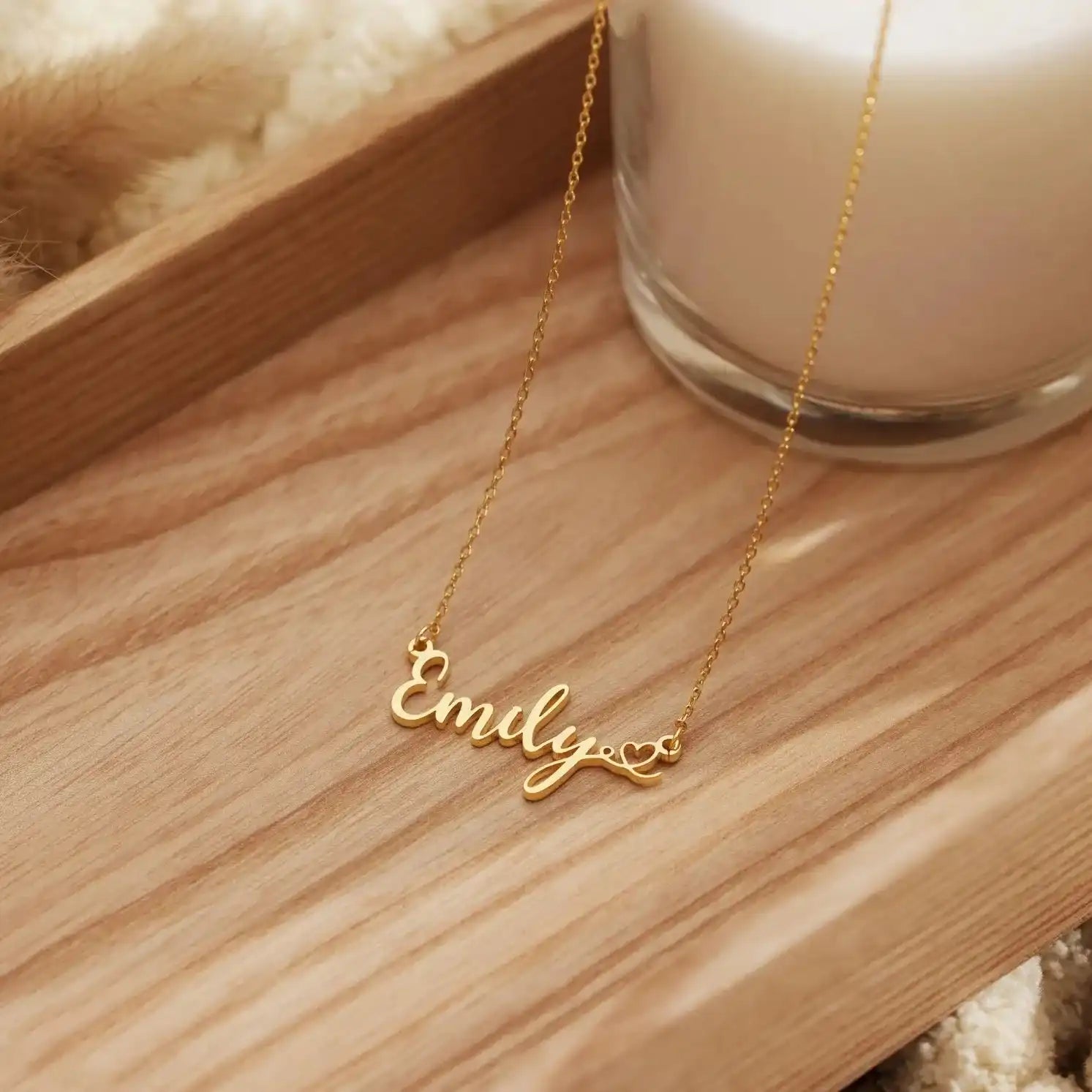 Gold chain necklace with Emily script nameplate and heart tail detail on wooden tray