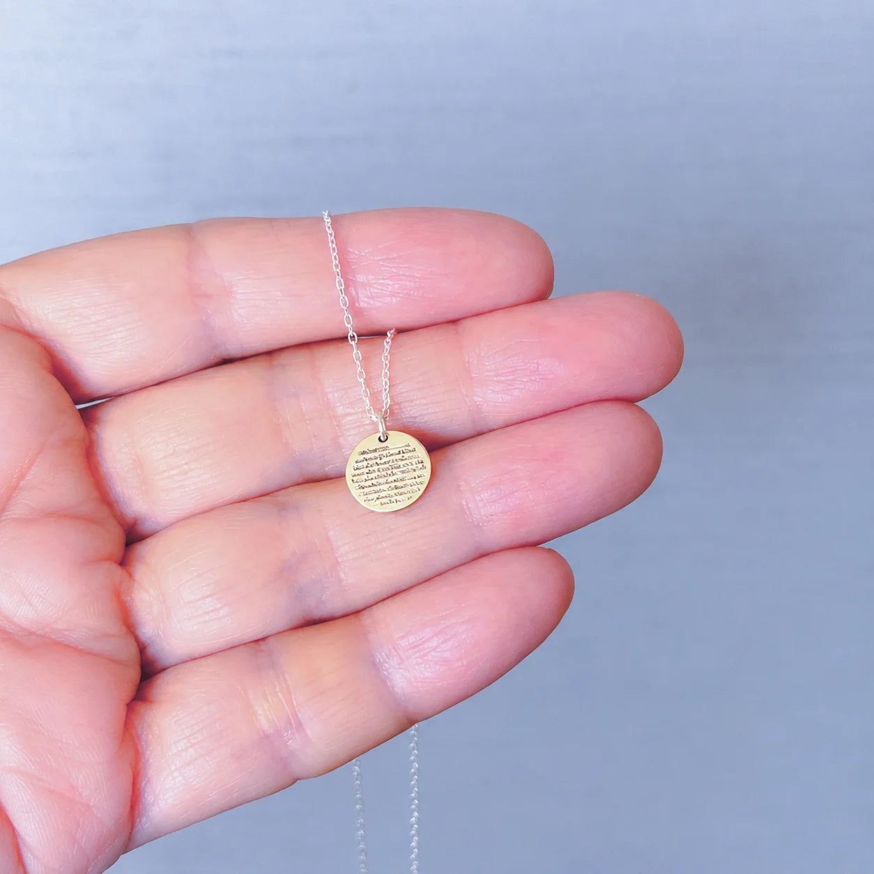 Gold Ayat ul Kursi pendant necklace with engraved Arabic calligraphy displayed on a hand, featuring a delicate chain and minimalist design.