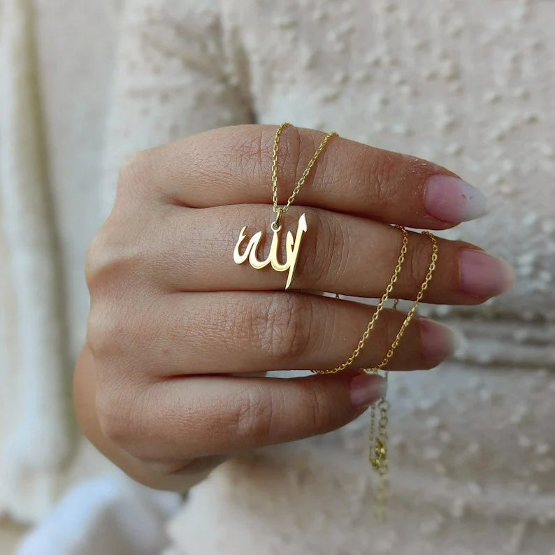 Gold Allah pendant necklace held in hand, featuring delicate chain detailing and custom Islamic calligraphic design.