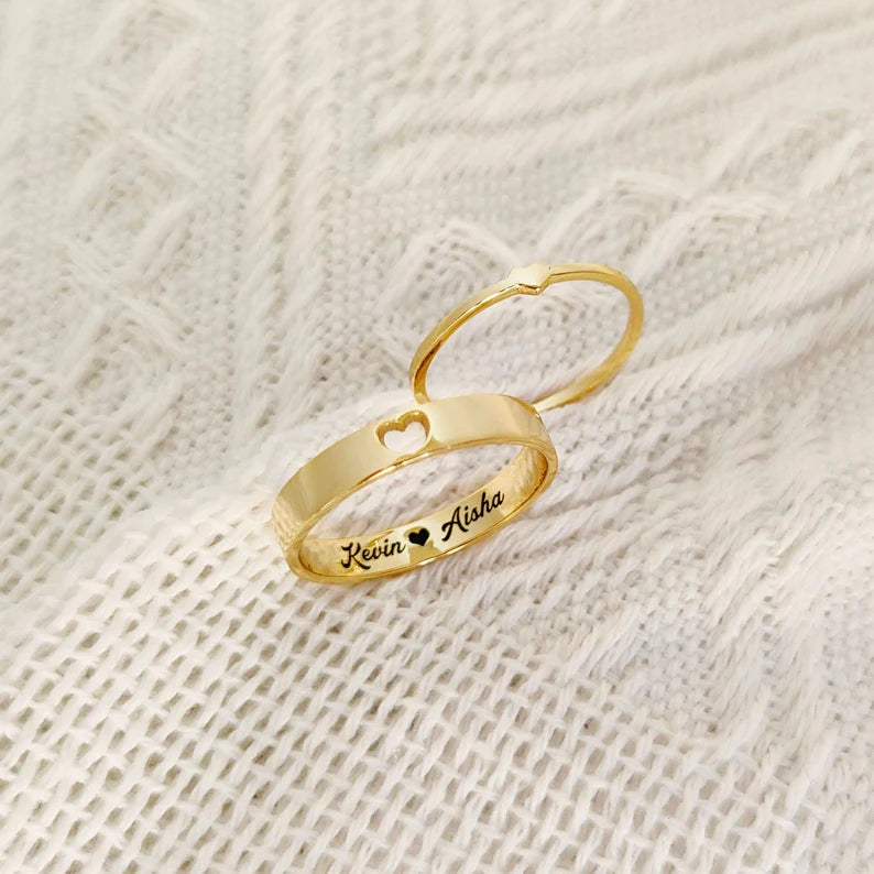 Gold couple rings with custom names engraved inside and a heart cutout detail
