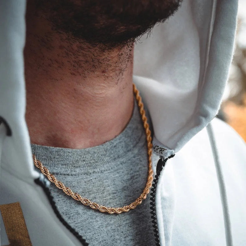 Man wearing gold twisted rope chain necklace over grey t-shirt and white hooded jacket