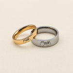 Gold and silver couple rings with engraved pinky promise designs on cream fabric