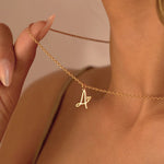 Woman holding thin gold chain with cursive letter A and heart pendant