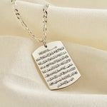 Men's sterling silver Ayatul Kursi necklace with engraved rectangular pendant displayed on a silver chain over a soft cream fabric background.