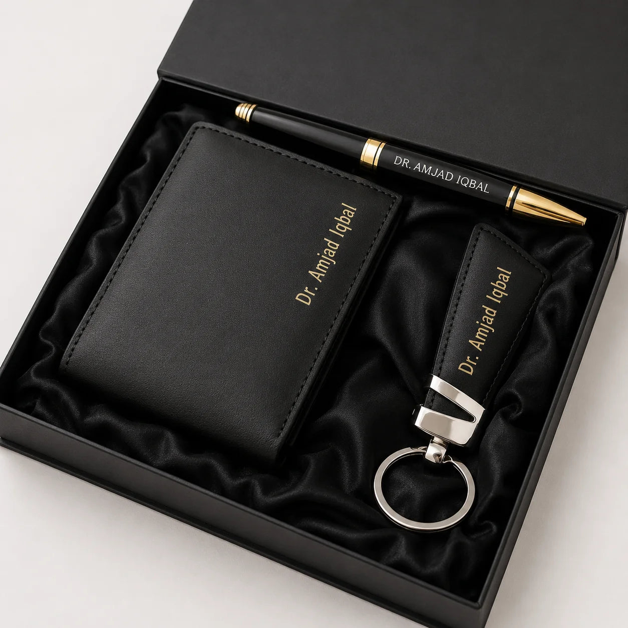 Premium black leather wallet gift set with matching keychain and pen featuring gold accents in an elegant presentation box.