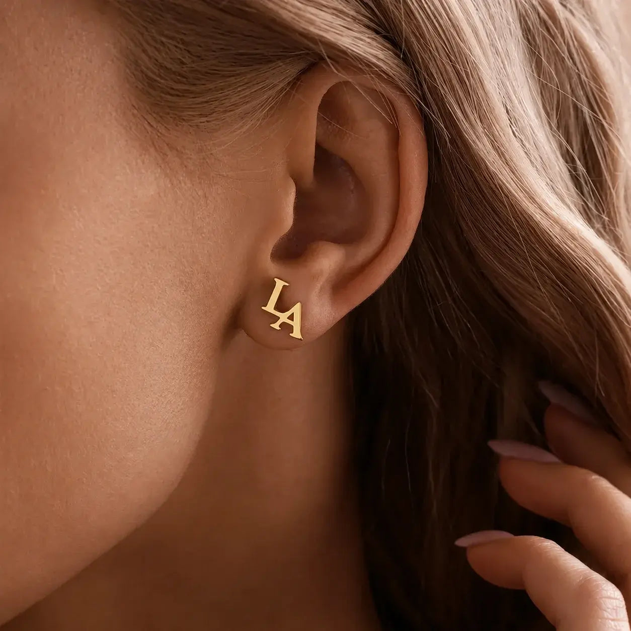 Double initial earrings featuring two personalised letter designs worn as elegant golden stud earrings.