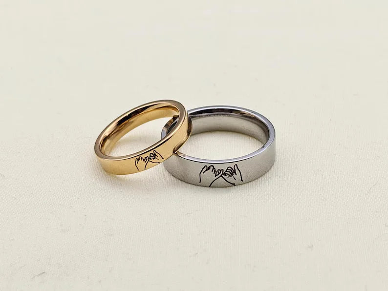 Gold and silver pinky promise rings featuring matching engraved hand gesture designs