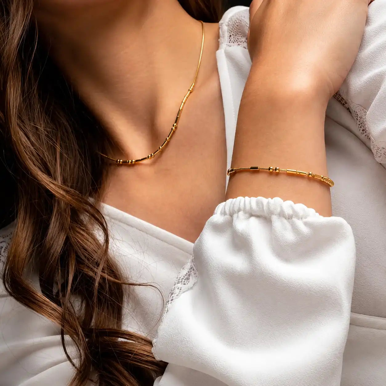 Gold personalized Morse code necklace and matching bracelet set worn by a woman.