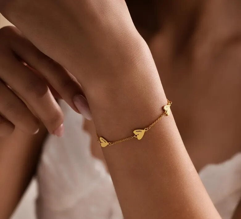 Personalized heart name bracelet with two custom engraved heart charms on a delicate chain, available in golden and silver finishes.