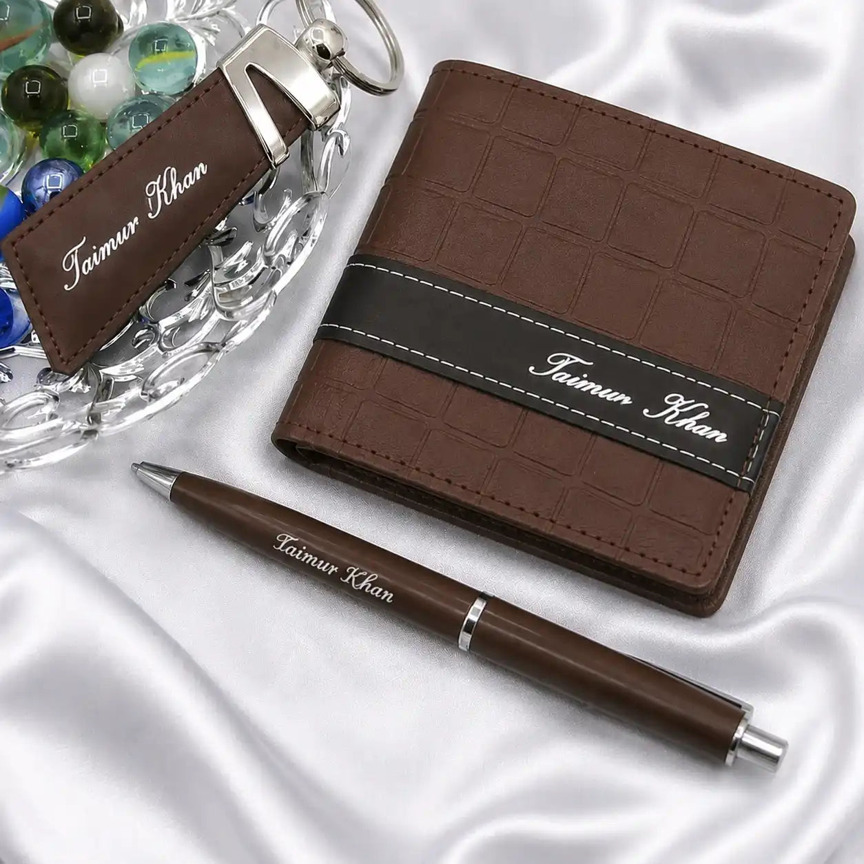 Personalized brown leather wallet with matching pen and keychain gift set featuring custom name detailing