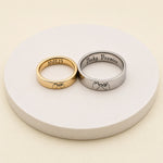 Gold and silver pinky promise rings with custom date and message engravings on a white display stand