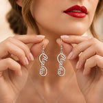 Personalized silver name earrings with custom script lettering held for display.