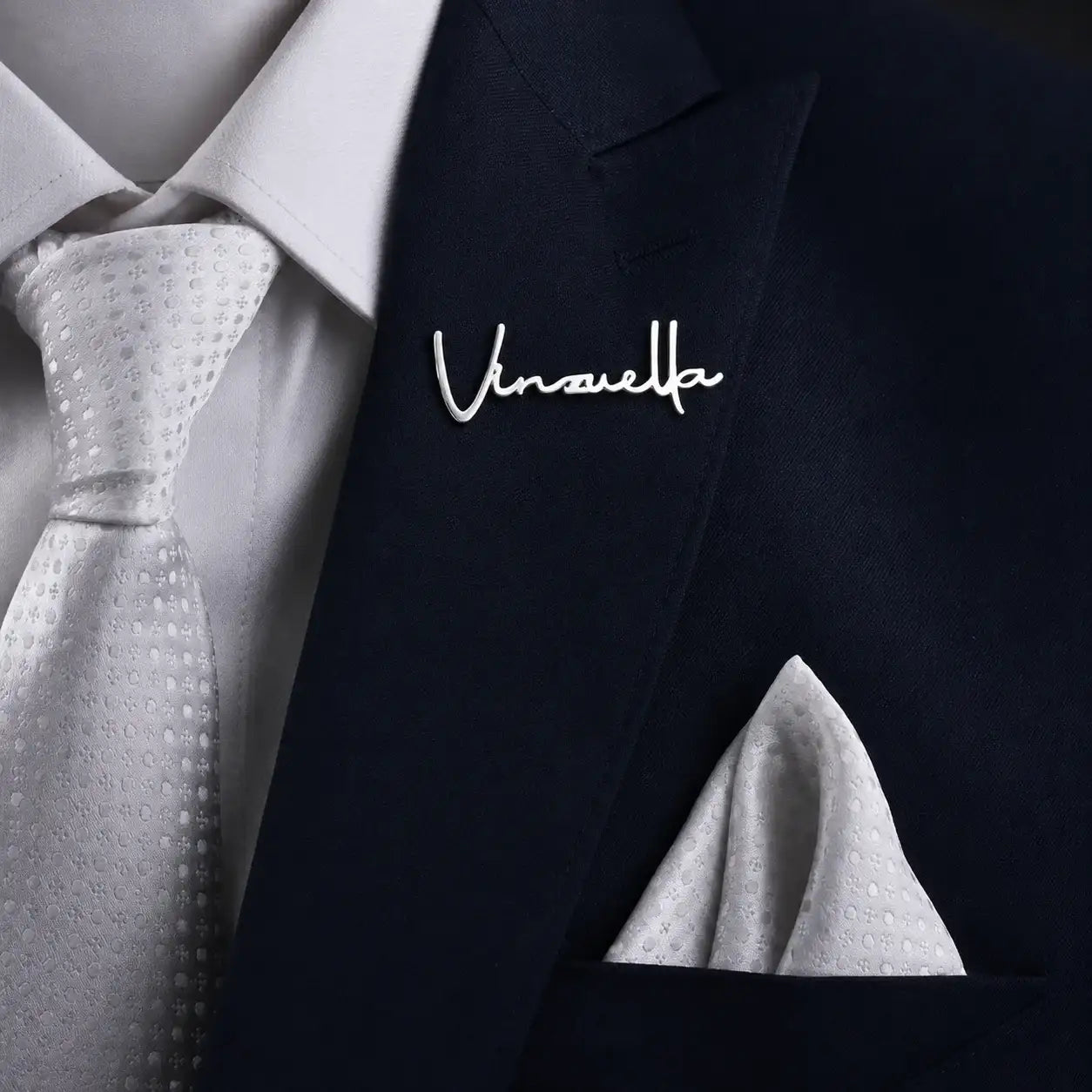 Personalized silver name lapel pin attached to a formal suit jacket.