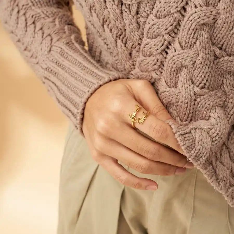 Woman wearing gold open band ring with custom cursive script names on pointer finger