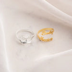 Hand wearing gold open wrap ring with custom cursive script names on index finger