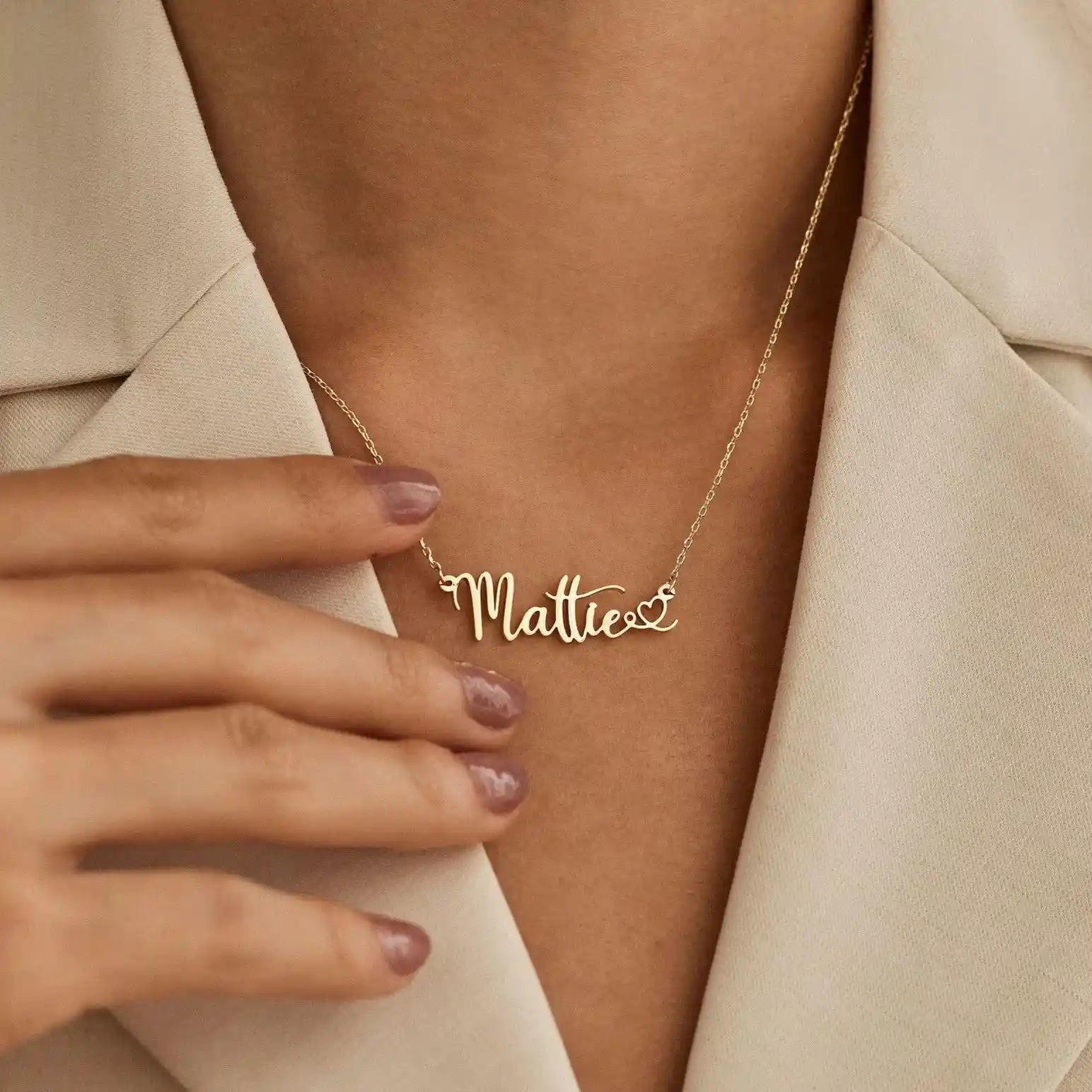Woman wearing gold chain necklace with Mattie script nameplate and heart tail charm