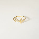A delicate gold script ring featuring the name 'Sofia' in cursive, displayed on a clean, light off-white background.