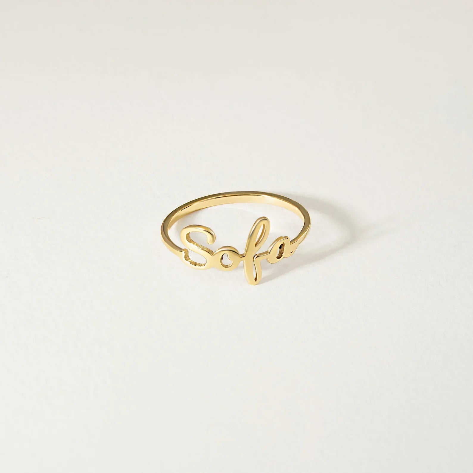A delicate gold script ring featuring the name 'Sofia' in cursive, displayed on a clean, light off-white background.