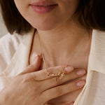 Woman holding gold chain necklace with delicate Emily script nameplate near neck