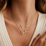 Woman wearing two layered gold chain necklaces with Ayana and Lydia script nameplates