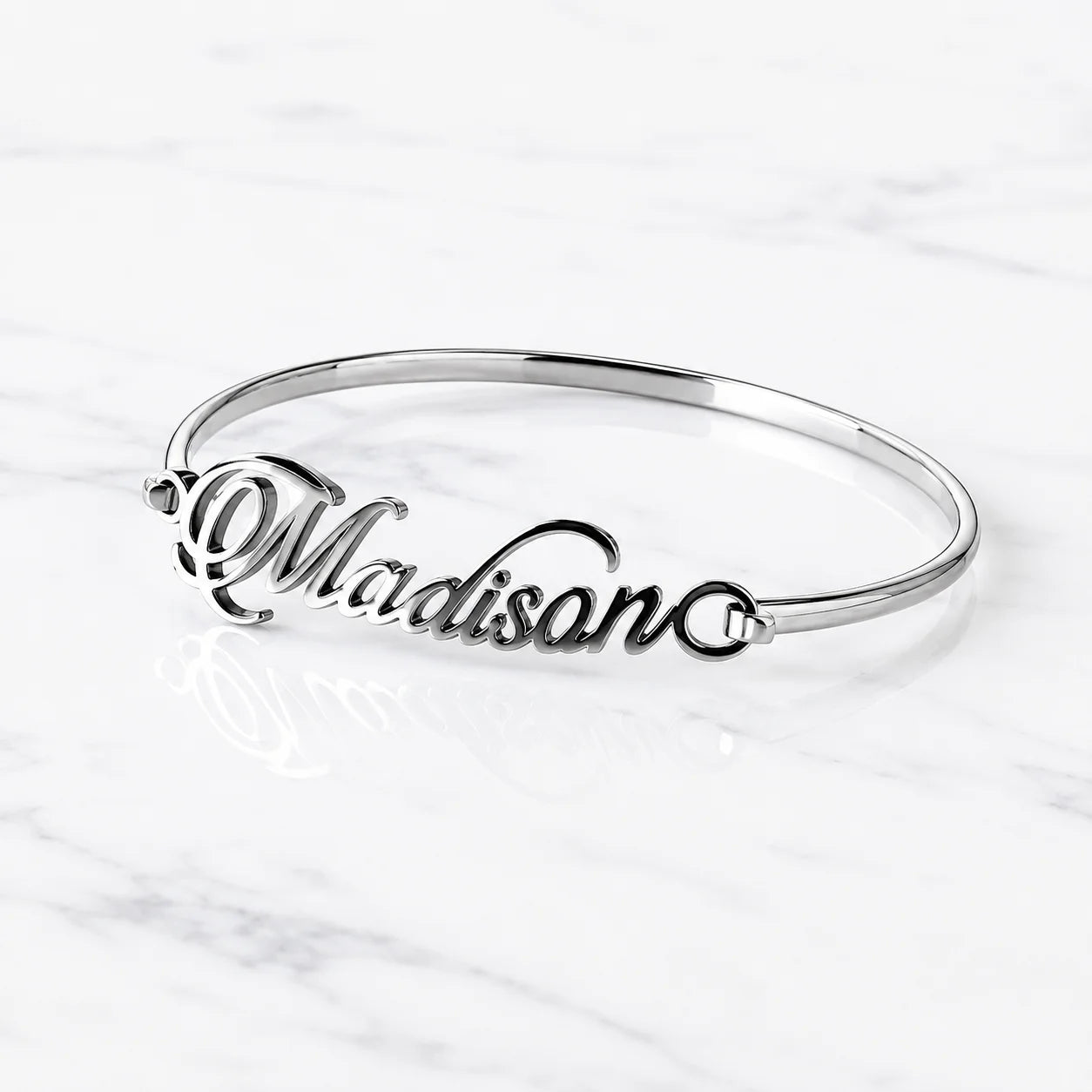 Madison silver name bangle with personalized cursive lettering on white marble background