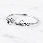 Madison silver name bangle with personalized cursive lettering on white marble background