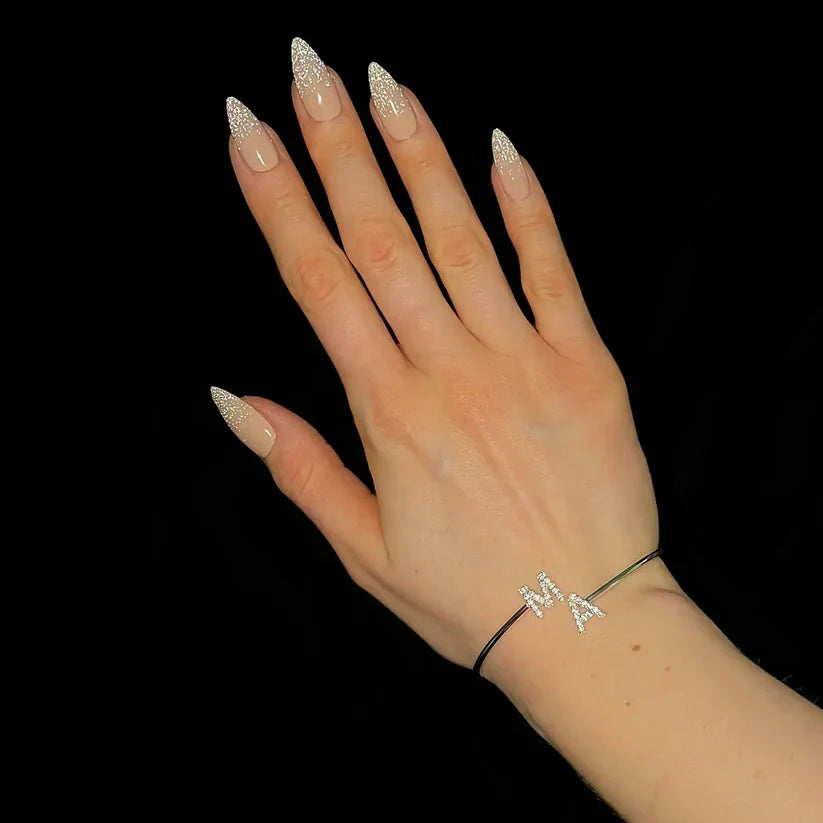 Silver open cuff bracelet with diamond M A initial charms on hand with stiletto nails