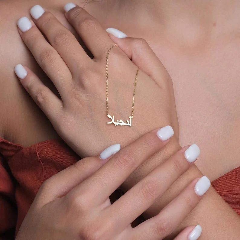 Gold custom Urdu name necklace held in hands 