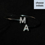 Silver custom initial cuff bracelet featuring diamond-paved M and A letter charms on a black surface